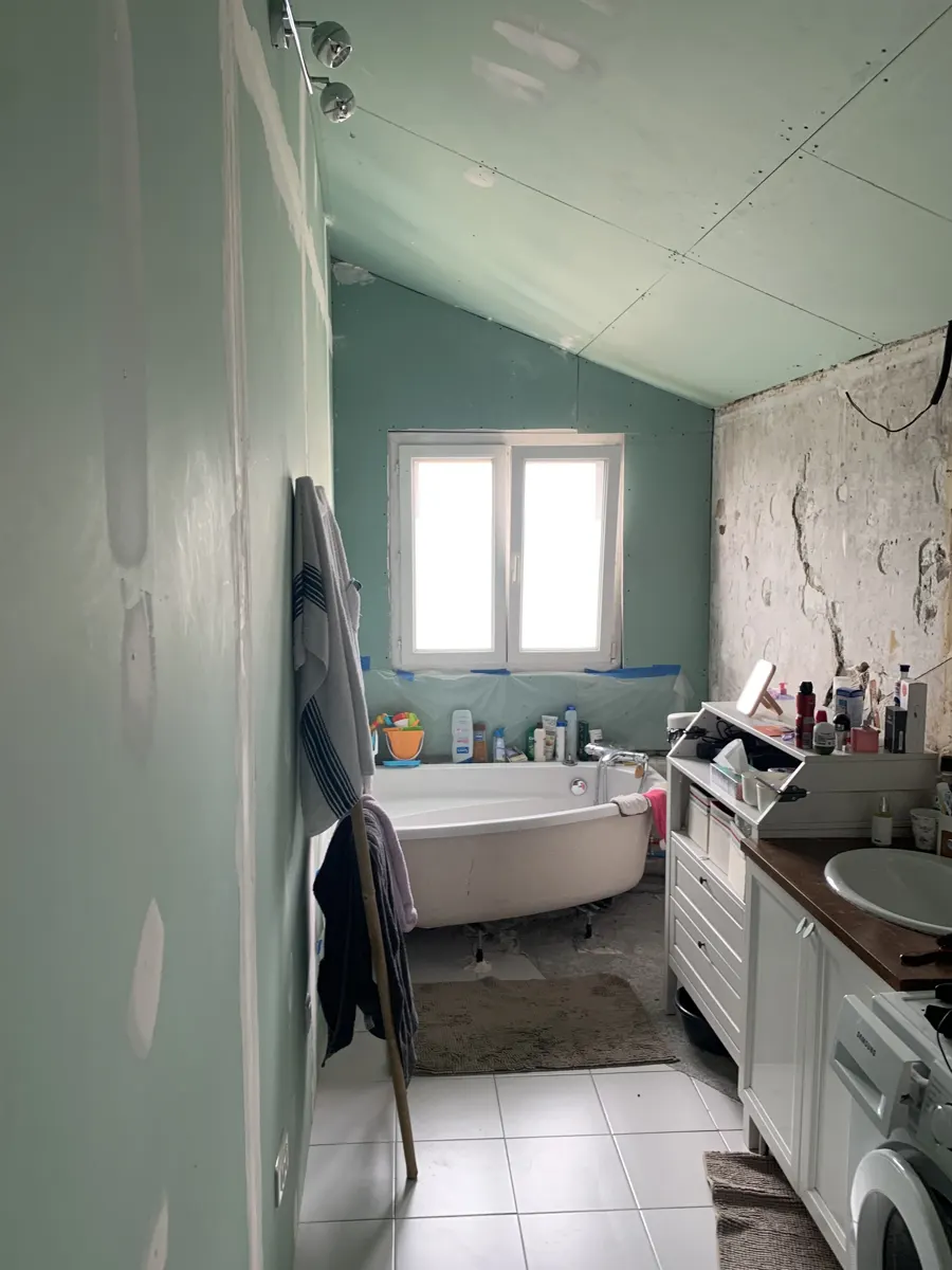 Salle de bain sous combles avant travaux : baignoire, murs abîmés